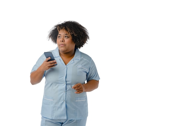 Jeune femme médicale afro-latine tenant son téléphone en regardant en pensant à l'espace de copie de fond blanc