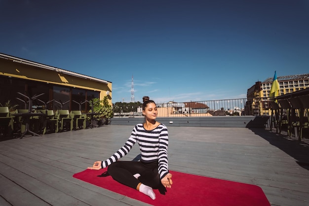 Jeune femme méditant en posture de lotus sur le toit de l'immeuble