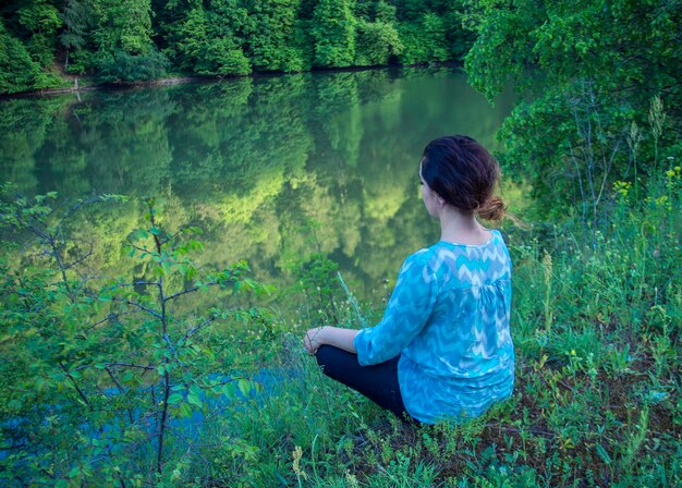 Une jeune femme médite au bord du lac.