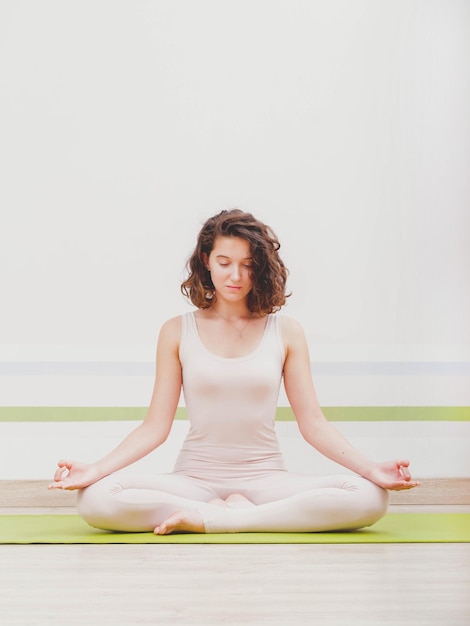 Une jeune femme médite dans un studio de yoga.