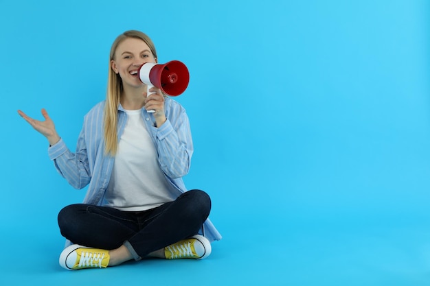 Jeune femme avec mégaphone sur fond bleu