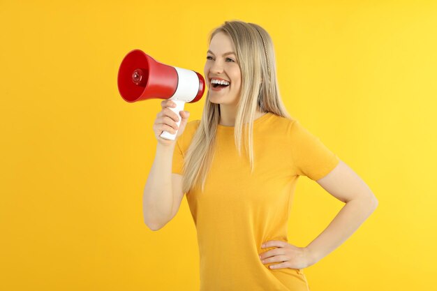 Jeune femme avec mégaphone sur fond jaune