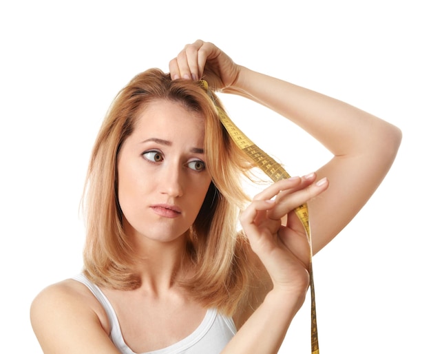 Jeune femme mesurant la longueur des cheveux sur fond blanc