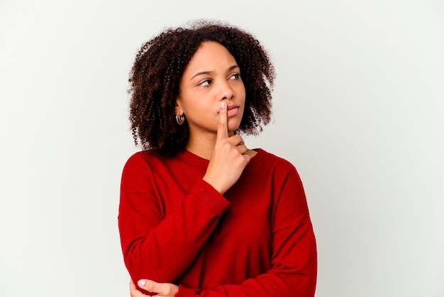 Jeune femme métisse afro-américaine isolée à la recherche sur le côté avec une expression douteuse et sceptique.