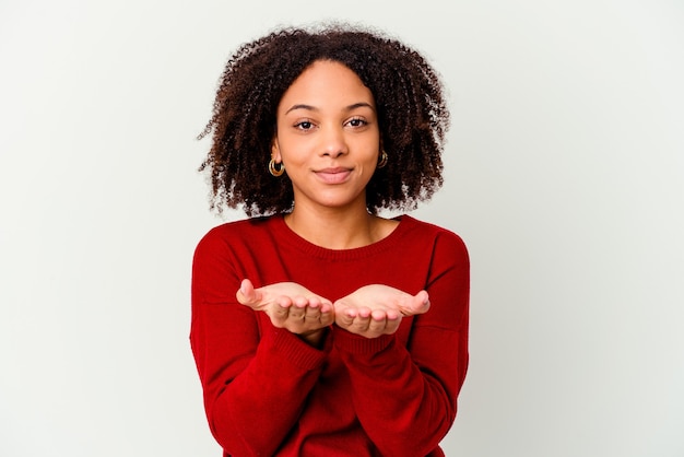 Jeune femme métisse afro-américaine isolée tenant quelque chose avec des palmiers, offrant.