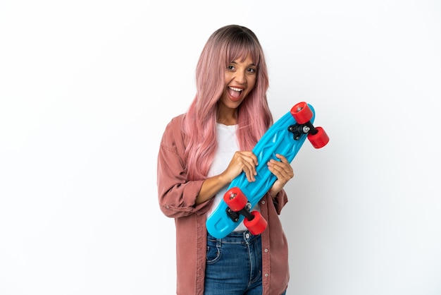 Jeune femme métisse aux cheveux roses isolée sur fond blanc avec un patin avec une expression heureuse