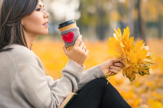 Jeune femme métisse buvant du café dans le parc d'automne