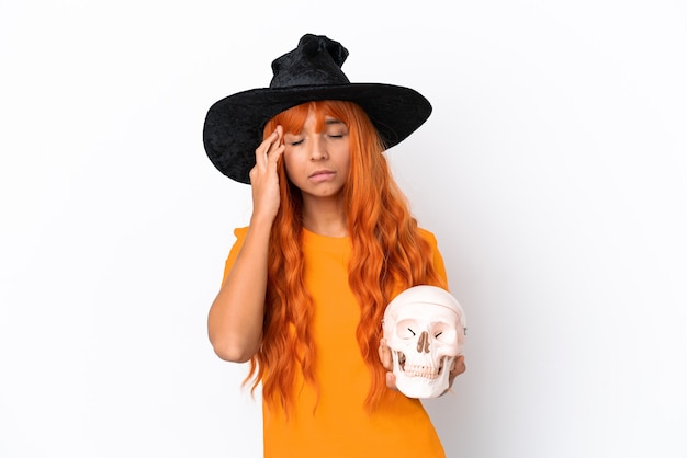 Jeune femme métisse déguisée en sorcière tenant un crâne isolé sur fond blanc avec des maux de tête