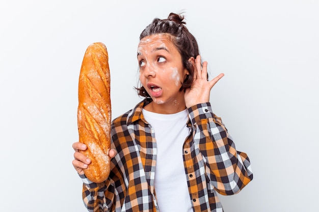 Jeune femme métisse faisant du pain isolé sur un mur blanc en essayant d'écouter un commérage.