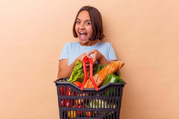 Jeune femme métisse faisant le shopping isolé sur mur beige