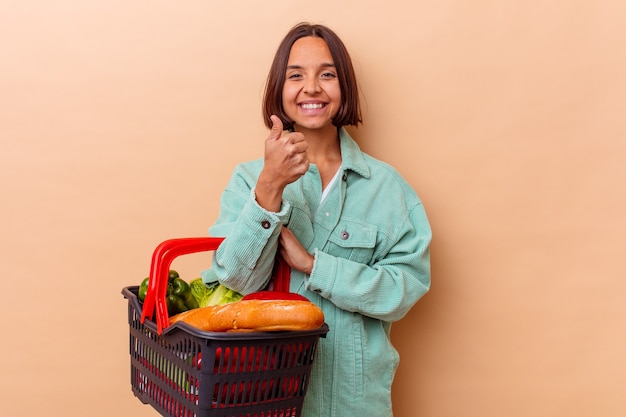 Jeune femme métisse faisant le shopping isolé sur mur beige