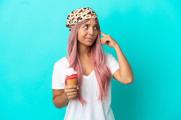 Jeune femme métisse avec une glace au cornet isolée sur fond bleu ayant des doutes et pensant