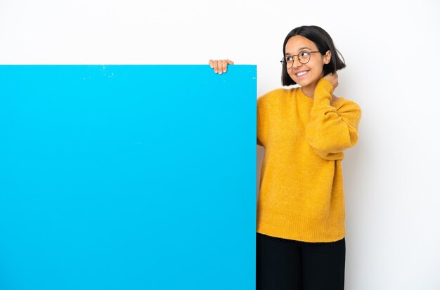 Jeune femme métisse avec une grande pancarte bleue isolée sur fond blanc en pensant à une idée