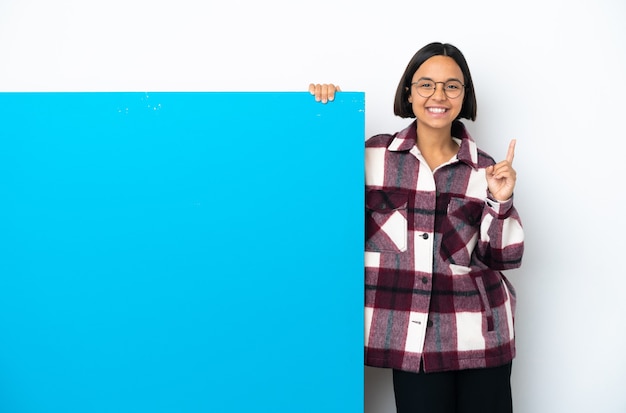 Jeune femme métisse avec une grande pancarte bleue isolée sur fond blanc pointant vers une excellente idée