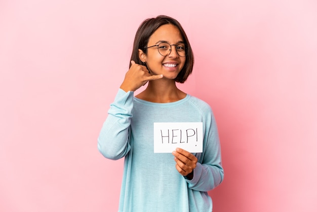 Jeune femme métisse hispanique tenant une affiche d'aide montrant un geste d'appel de téléphone mobile avec les doigts.