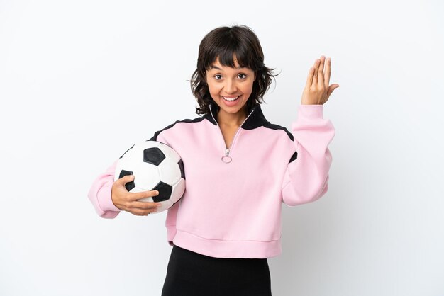 Jeune femme métisse isolée sur fond blanc avec ballon de foot et faisant un geste à venir