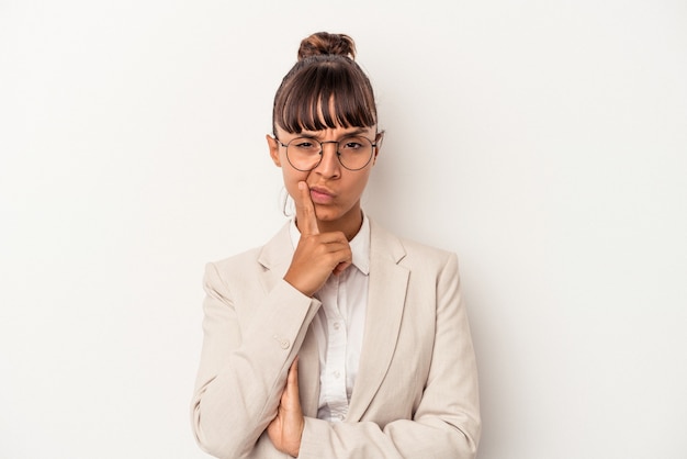 Jeune femme métisse isolée sur fond blanc contemplant, planifiant une stratégie, réfléchissant à la manière d'une entreprise.