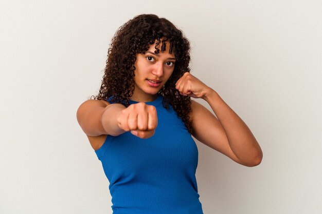 Jeune femme métisse isolée sur fond blanc jetant un coup de poing, colère, combat à cause d'une dispute, boxe.