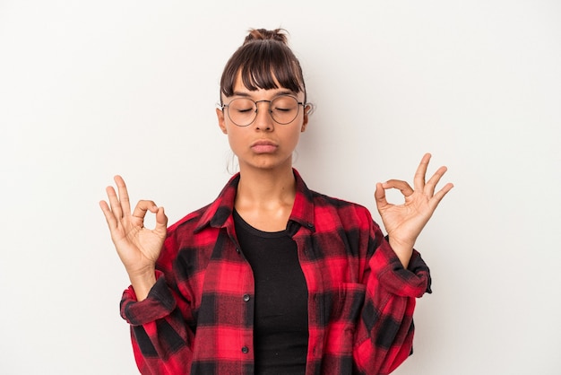 Jeune femme métisse isolée sur fond blanc se détend après une dure journée de travail, elle fait du yoga.