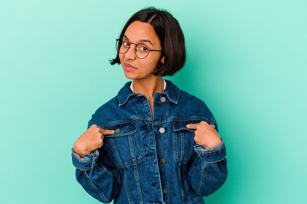 Jeune femme métisse isolée sur fond bleu personne pointant à la main vers un espace de copie de chemise, fière et confiante