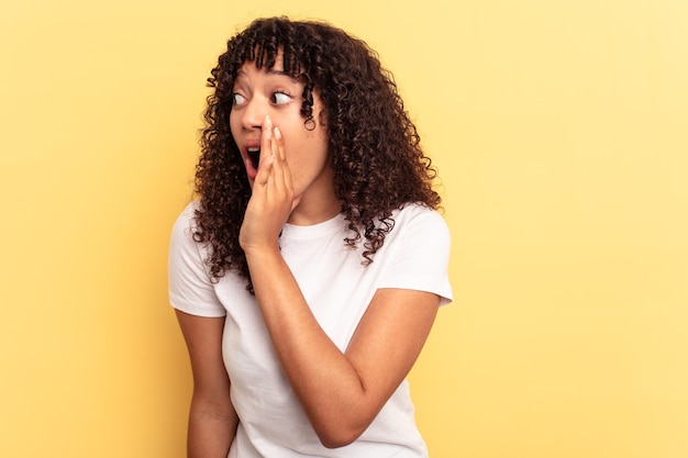 Jeune femme métisse isolée sur fond jaune choquée à cause de quelque chose qu'elle a vu.