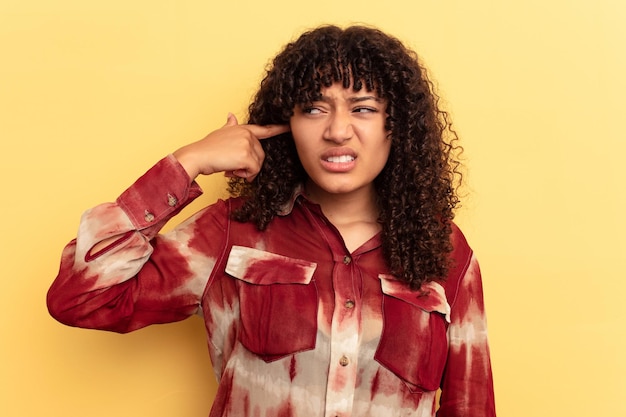 Jeune femme métisse isolée sur fond jaune couvrant les oreilles avec les mains