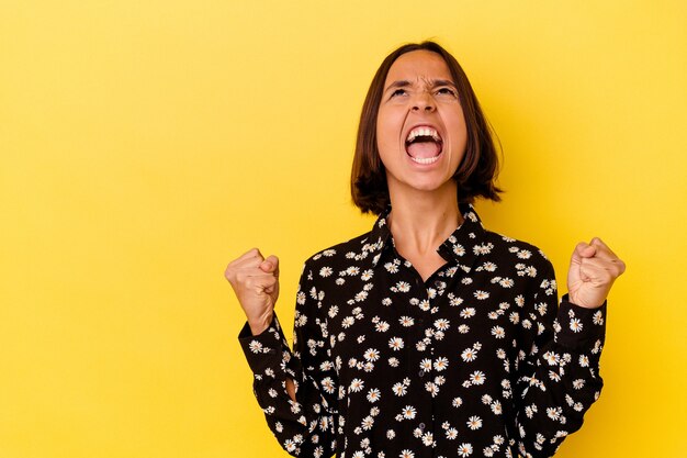 Jeune femme métisse isolée sur fond jaune criant très en colère, concept de rage, frustré.