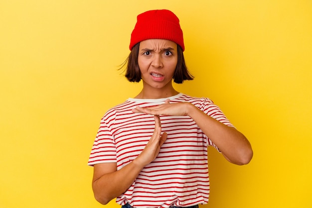 Jeune femme métisse isolée sur fond jaune montrant un geste de temporisation.