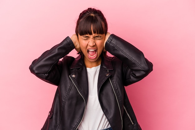 Jeune femme métisse isolée sur fond rose couvrant les oreilles avec les mains essayant de ne pas entendre un son trop fort.