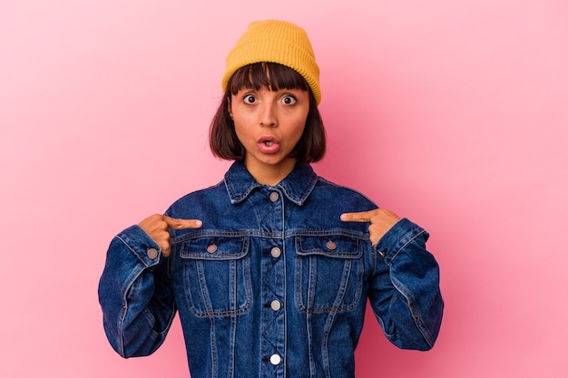 Jeune femme métisse isolée sur fond rose pointe vers le bas avec les doigts, sentiment positif.