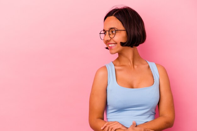 Jeune femme métisse isolée sur fond rose souriant confiant avec les bras croisés.