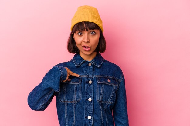 Jeune femme métisse isolée sur fond rose surpris en pointant avec le doigt, souriant largement.