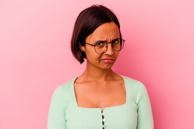 Jeune femme métisse isolée sur fond rose, visage triste et sérieux, se sentant misérable et mécontent.