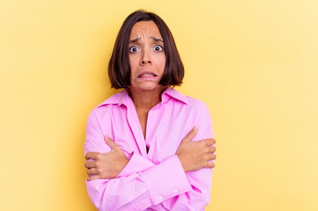 Jeune femme métisse isolée sur un mur jaune qui fait froid en raison d'une température basse ou d'une maladie.