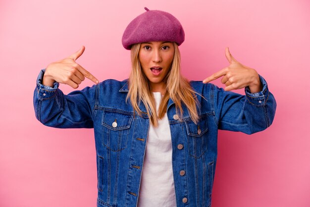 Jeune femme métisse isolée sur les points roses vers le bas avec les doigts, sentiment positif.