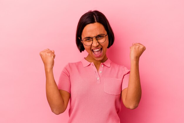 Jeune femme métisse isolée sur rose applaudissant insouciant et excité