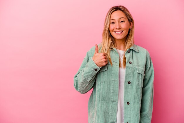 Jeune femme métisse isolée sur rose souriant et levant le pouce vers le haut