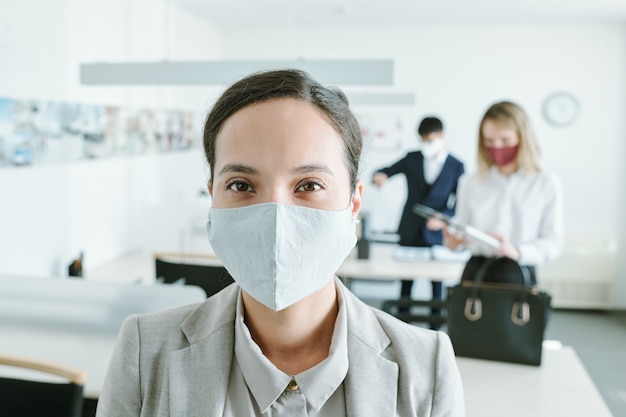 Jeune femme métisse en masque de protection avec ses collègues par leur bureau d'aller travailler