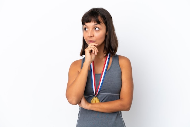 Photo jeune femme métisse avec des médailles isolées sur fond blanc ayant des doutes et avec une expression de visage confuse