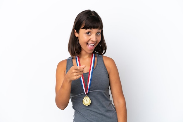 Jeune femme métisse avec des médailles isolées sur fond blanc pointe le doigt vers vous avec une expression confiante