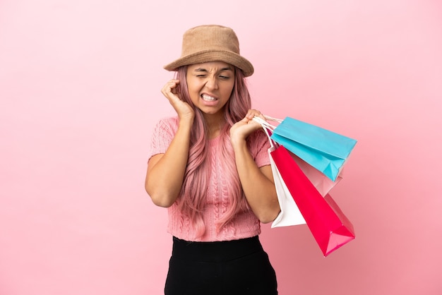 Jeune femme métisse avec panier isolé sur fond rose frustré et couvrant les oreilles