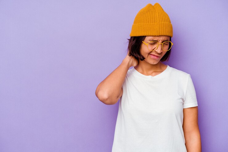 Photo jeune femme métisse portant un bonnet de laine isolé sur fond violet touchant l'arrière de la tête, en pensant et en faisant un choix.