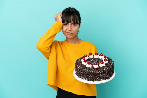 Jeune femme métisse tenant un gâteau d'anniversaire avec une expression de frustration et de ne pas comprendre