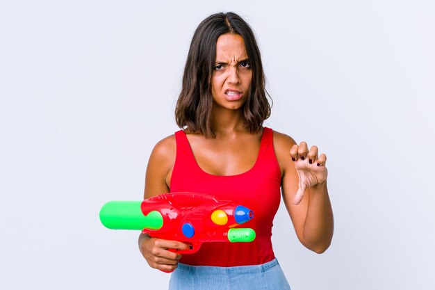 Jeune femme métisse tenant un pistolet à eau isolé montrant le pouce vers le bas et exprimant l'aversion.