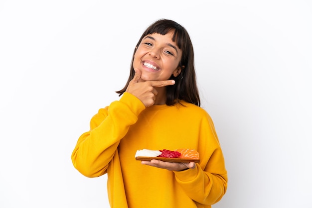 Jeune femme métisse tenant sashimi isolé sur fond blanc heureux et souriant