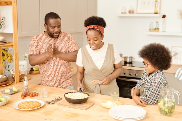 Jeune femme mettant la poêle avec des pâtes sur la table