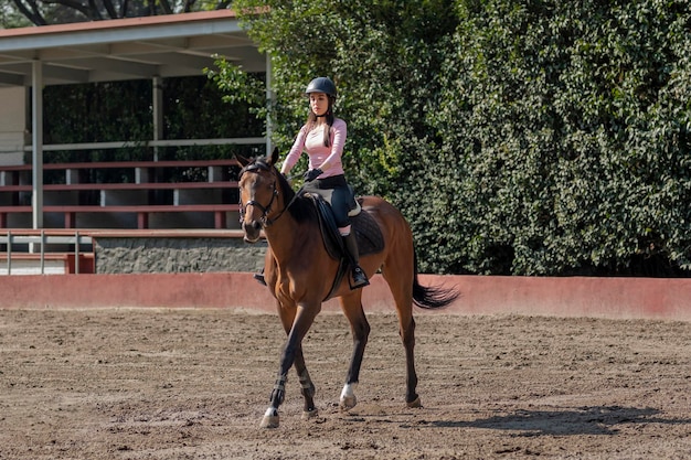 Une jeune femme mexicaine à cheval dans l'arène d'un centre équestre