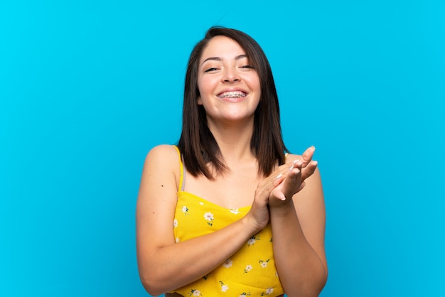 Jeune femme mexicaine sur fond bleu isolé applaudissant