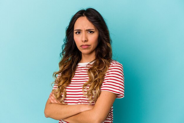 Jeune femme mexicaine isolée sur bleu suspect, incertain, vous examinant.