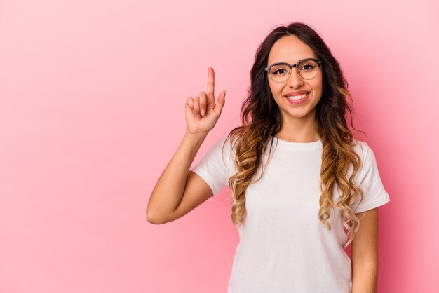 Jeune femme mexicaine isolée sur fond rose montrant le numéro un avec le doigt.